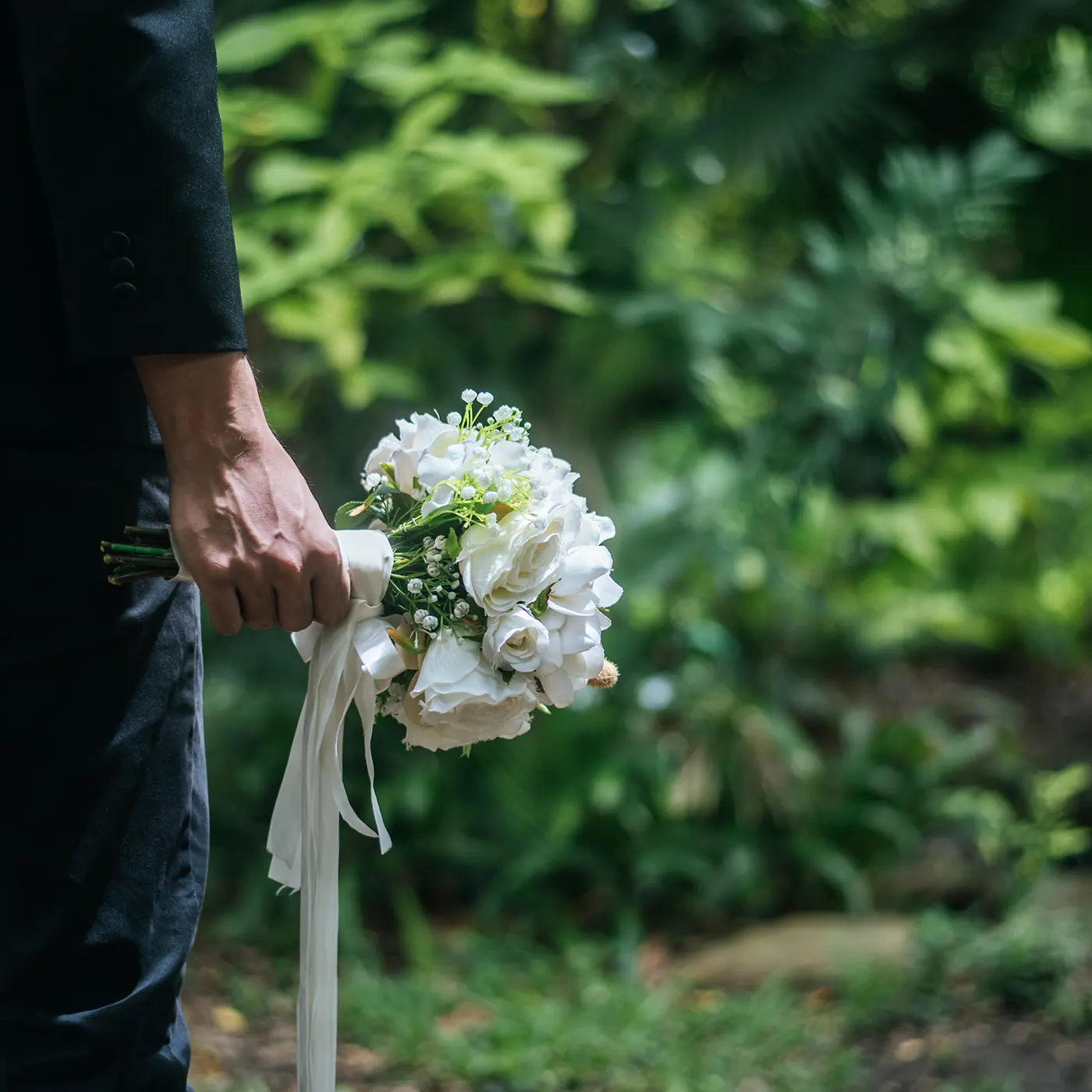 Trauernder mit weißem Blumenstrauß im Grünen
